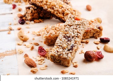 Various granola chocolate energy bars in row with scattered mixed nuts, cereals & dried fruit, grunged white wood table background. Healthy vegan fitness food snack. Top view, copy space, close up. - Powered by Shutterstock
