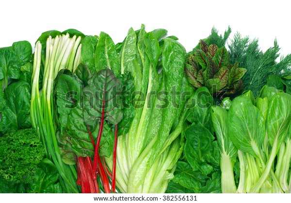 Various green leafy vegetables in row on white\
background. Top view\
point.