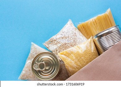 Various grocery products in packages top view. Pasta, cereals and canned food in paper bag on blue background. Food delivery, donation or stock provision concept. Copy space. - Shutterstock ID 1731606919