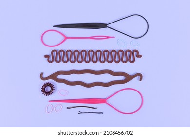 Various Hair Styling Tools Like Bun Maker, Braid Tool, Ponytail Style Maker, Hair Clip, Rubber Bands And Pins On Violet Background