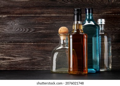 Various hard liquor bottles. Gin, vodka, tequila and whiskey in front of wooden wall with copy space