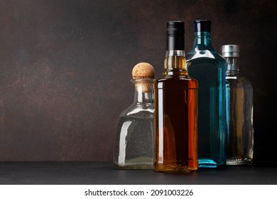 Various hard liquor bottles. Gin, vodka, tequila and whiskey in front of wooden wall with copy space