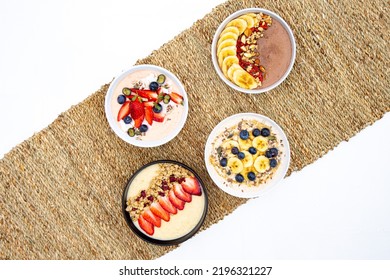 Various Healthy Bowls Of Cereal With Fruit Placed On A Rustic Table Runner Isolated On A White Background