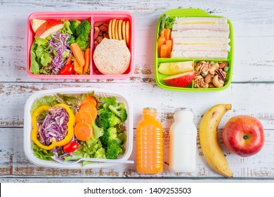 Various Of Healthy Lunch Boxes Of Sandwich. Kid Bento Pack For School Set In Plastic Package, Salad Box, Banana And Apple With Orange Juice, Milk. Top View.