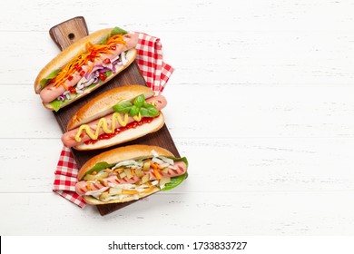 Various hot dog with vegetables, lettuce and condiments on wooden background. Top view with copy space. Flat lay