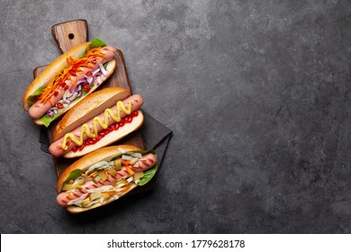 Various hot dog with vegetables, lettuce and condiments on stone background. Top view with copy space. Flat lay
