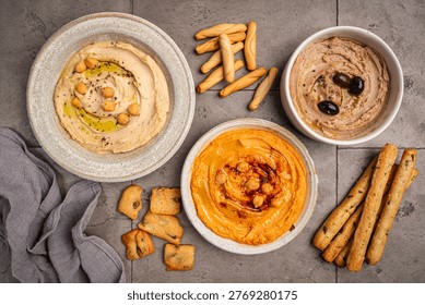 Various hummus dips in different colours. Hummus with dry crackers, top view. Vegan and traditional hummus as healthy and vegan snack.