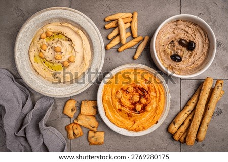 Various hummus dips in different colours. Hummus with dry crackers, top view. Vegan and traditional hummus as healthy and vegan snack.