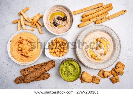 Various hummus dips in different colours. Hummus with dry crackers, top view. Vegan and traditional hummus as healthy and vegan snack.