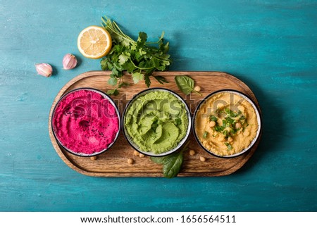 Various hummus dips, flat lay of hummus in different colours with spinach, beetroot and vegetables, vegan snack