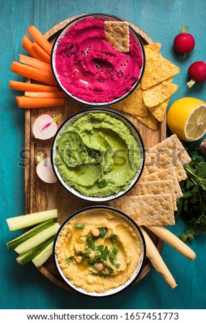 Various hummus dips, flat lay of hummus in different colours with egetables, healthy snack