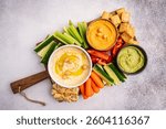 Various hummus dips. Hummus plate with vegetable snacks. Carrot, cucumber, tomato, celery sticks, dry crackers and olive, top view. Vegan and traditional hummus as healthy and vegan snack.