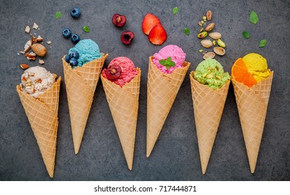Various of ice cream flavor in cones blueberry ,strawberry ,pistachio ,almond ,orange and cherry setup on dark stone background . Summer and Sweet menu concept.