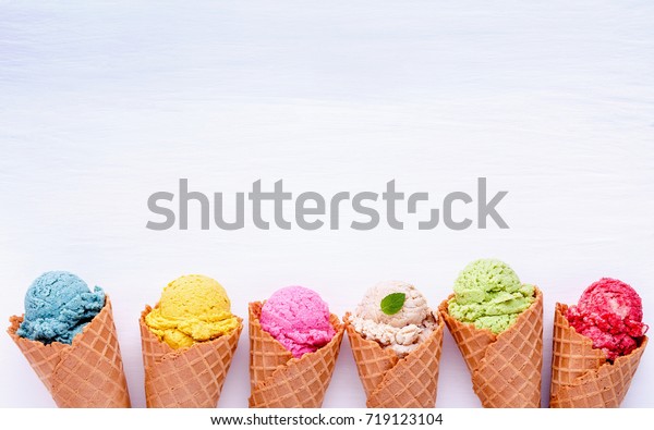 Various of ice cream\
flavor in cones blueberry ,strawberry ,pistachio ,almond ,orange\
and cherry setup on white wooden background . Summer and Sweet menu\
concept.