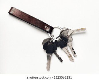 Various keys in the genuine leather keychain on isolated white background.