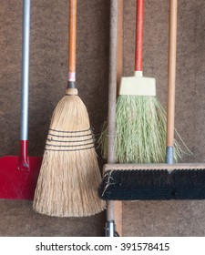 Various kind of brooms and a sidewalk ice scraper hanging on pegboard wall in the garage - Shutterstock ID 391578415