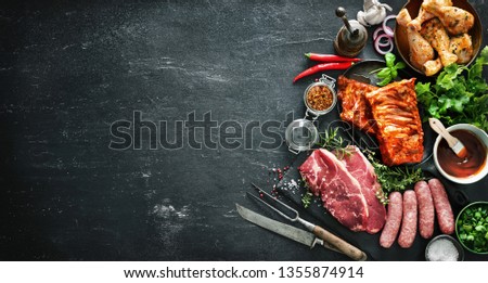 Various kinds of grill and bbq meats with vintage kitchen and butcher utensils. Chicken legs, steaks, sausages, pork ribs with herbs, spices, sauces and ingredients for grilling Stock fotó © 