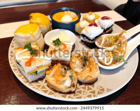 Various kinds of offerings on the table at an afternoon tea meal consisting of various kinds of cakes, bread, sandwiches and other snacks. Afternoon tea is usually found in five-star hotel services.