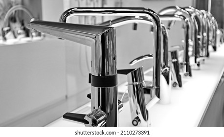Various Kitchen Faucets In A Row. Reduce Your Water Consumption Using A Smart Faucet. Touchless Or Manual Operation. Black And White Photo