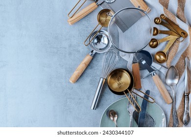 various kitchen utensils on a striped kitchen towel on a gray concrete background. sieve, measuring spoons, knives, pizza cutter. space for text - Powered by Shutterstock