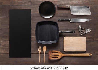 Various kitchenware utensils on the wooden background.