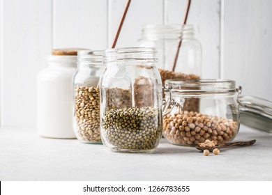 Various Legumes: Beans, Chickpeas, Buckwheat, Lentils In Glass Jars On A White Background. Healthy Vegetarian Food, Vegetable Protein, Plant Based Diet Concept.