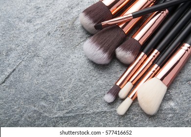 Various makeup brushes on black stone