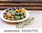 various of Mediterranean pickled olives in a plate over rustic background - Mediterranean meze appetizer or tapas