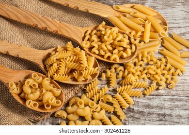 Various mix of pasta on wooden rustic background, sack and wooden spoons. Diet and food concept. - Powered by Shutterstock