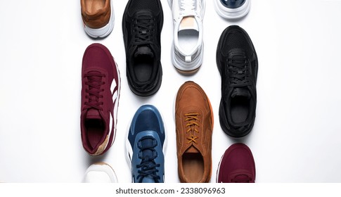 Various multi-colored pairs of men's sneakers on white background top view. Sports shoes for men or women, footwear for running, fitness, healthy lifestyle. Minimal background with sneakers