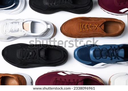 Various multi-colored pairs of men's sneakers on white background top view. Sports shoes for men or women, footwear for running, fitness, healthy lifestyle. Minimal background with sneakers