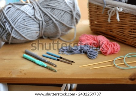 Various needlecraft supplies on the table. Colorful rainbow bookshelf in the background. Selective focus.