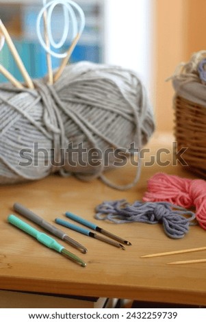 Various needlecraft supplies on the table. Colorful rainbow bookshelf in the background. Selective focus.
