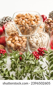 Various nuts and christmas flowers,butcher broom designed together on white surface.Conceptual image - Shutterstock ID 2396502605