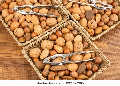 Various nuts with nutcrackers in three containers on brown background.