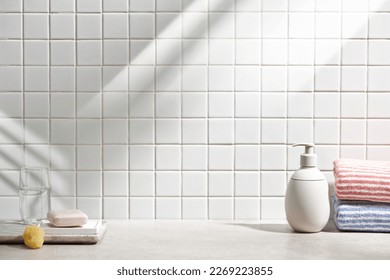 Various objects on a white tile background with warm sunlight shining through
