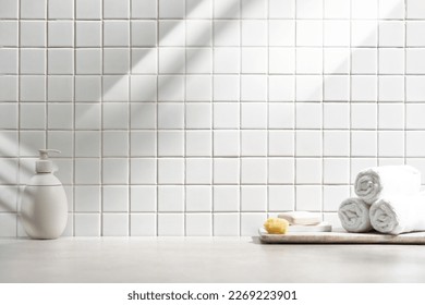 Various objects on a white tile background with warm sunlight shining through

