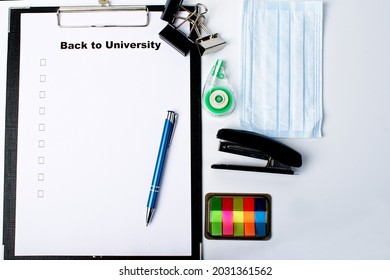 Various office supplies. Tablet with sheet of paper with a to-do list for study. Nearby is a mask, notebook, pens, stapler, stickers, proofreader, paper clips. School or university preparation