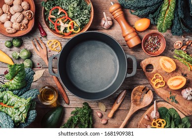 Various organic vegetables ingredients and empty iron cooking pot, wooden bowls, spoons on wooden background. Top view, copy space. Organic vegetables ingredients for vegan cooking. Clean eating food - Powered by Shutterstock