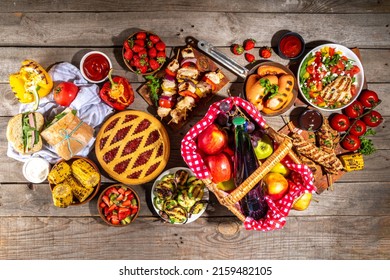 Various Picnic Barbeque Food And Drink Flatlay. Summer Bbq Picnic Food, Assorted Grilled Meats, Kebabs, Vegetable, Fruit Salad, Traditional Picnic Summer Pie Cake, Sandwiches, Top View Copy Space