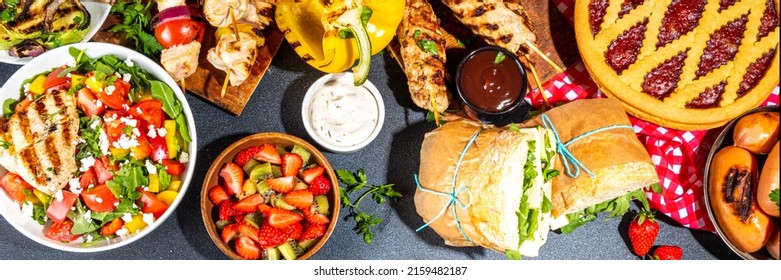 Various Picnic Barbeque Food And Drink Flatlay. Summer Bbq Picnic Food, Assorted Grilled Meats, Kebabs, Vegetable, Fruit Salad, Traditional Picnic Summer Pie Cake, Sandwiches, Top View Copy Space