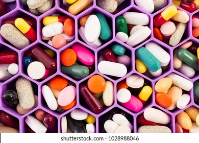 Various pills and capsules on cellular comb organizer tray as daily vitamins and supplements dosage routine concept