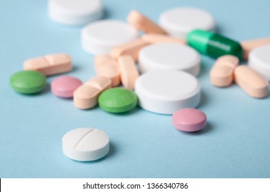 Various Pills, Small Tablets Of Medicine And Capsules On Blue Background; Safe Drug Use Concept. Selective Focus