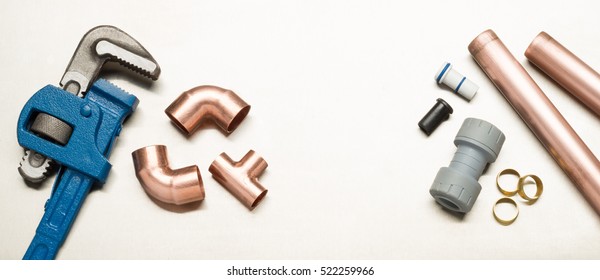 Various plumbers tools and plumbing materials including copper pipe, elbow joint, wrench and spanner. shot on a bright stainless steel background.