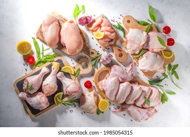Various raw chicken meat portions. Set of uncooked chicken fillet, thigh, wings, strips and legs on white cooking table background with spices 