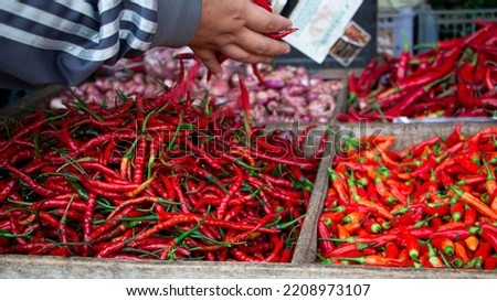 various red chilies in a wooden basket on the background of the seller and buyer's hands of vegetables