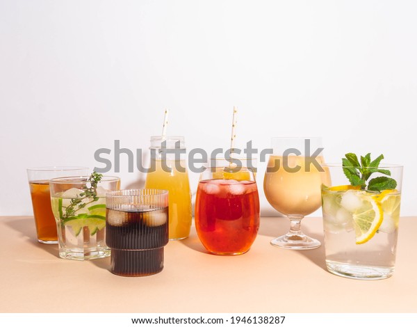 Various\
refreshing non-alcoholic drinks in glasses with ice. Different\
juice, homemade lemonade, iced coffee, iced fruit tea and smoothies\
on beige background. Copy space. Front\
view