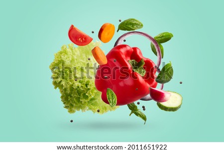 Various ripe vegetables levitating in the air over blue background. Fresh bell-pepper, lettuce, carrot, tomatoe, basil leaves, cucumber, onion, peas floating up, healthy recipes for summer concept