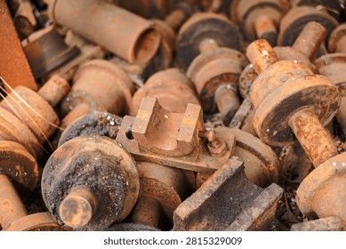 Various rusted metal weights and components are gathered in a yard. The scene shows the effects of weather and time on these items. The colors show different levels of rust and decay.
