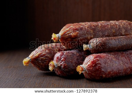 various salami sausages on dark brown table